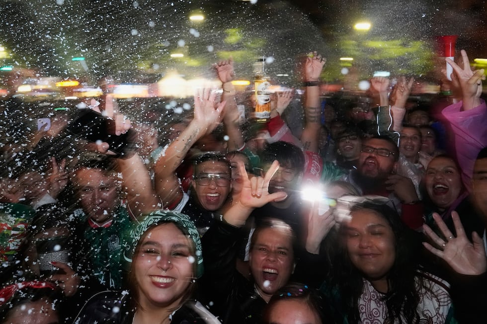 Fans celebrate on Reforma Ave., near the Angel of Independence monument in Mexico City, after...