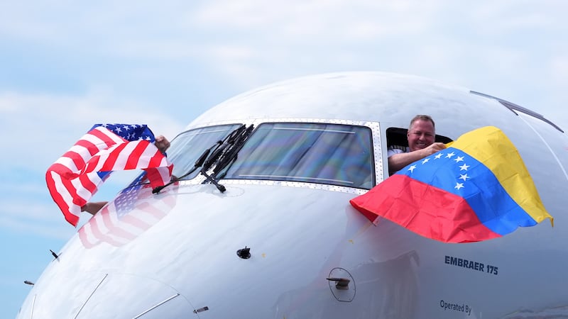 El capitán Ric Wilson ondea una bandera venezolana y el primer oficial saluda a la bandera...