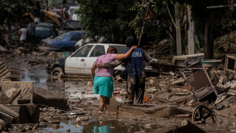 Un elemento de la Marina de México ayuda a una mujer a cruzar una calle inundada en Poza Rica,...