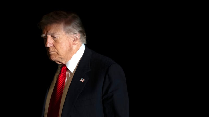 El presidente de Estados Unidos, Donald Trump, es iluminado por el flash de una cámara a su...